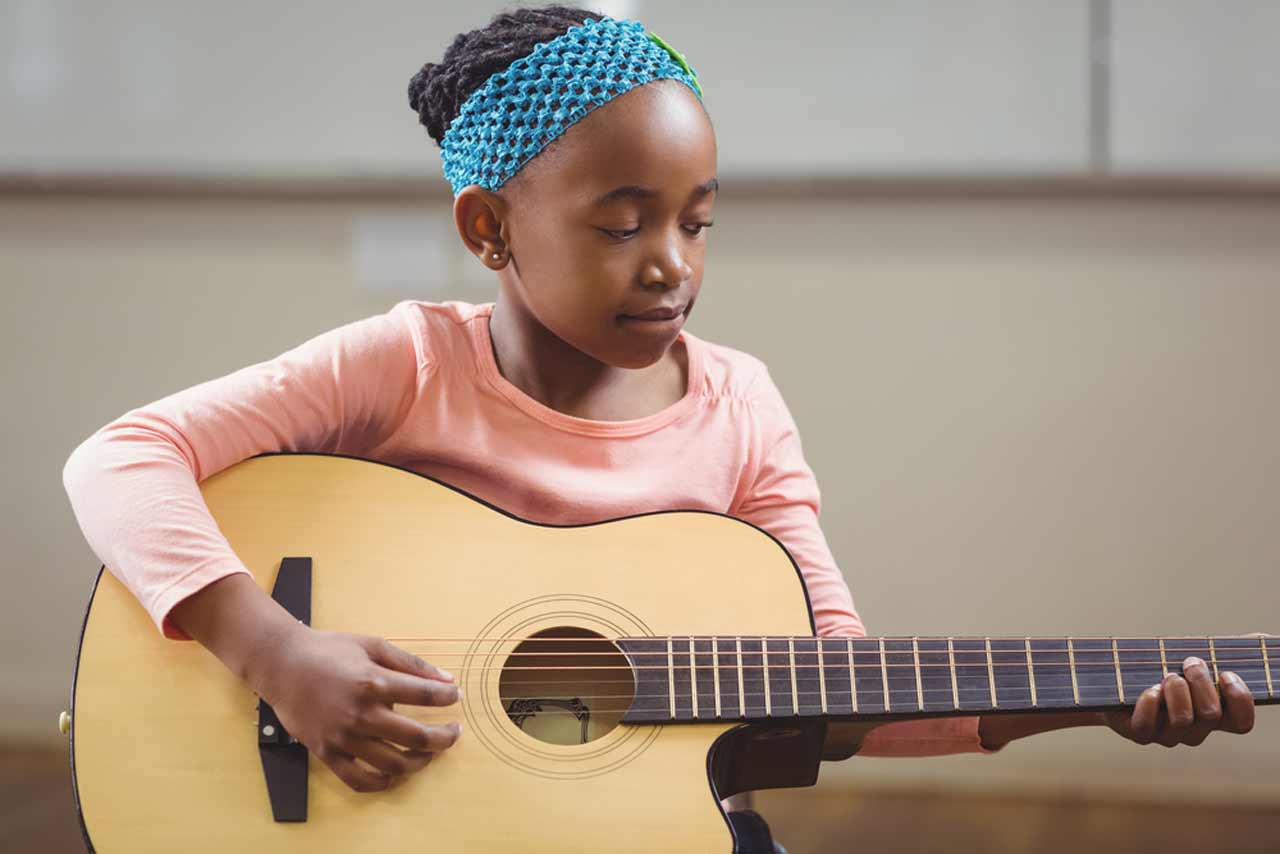 A little guitar plays at a guitar lesson in Glenview, IL.